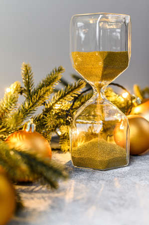 Christmas background, hourglass with Golden sand, fir branches and Christmas toys. The concept of the approaching holiday. Happy new yearの写真素材