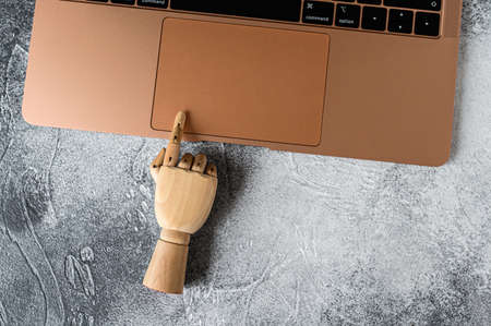 Wooden hand working at a laptop. Concept of communication and work in the officeの写真素材