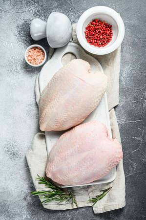 Raw chicken Breasts on a white chopping Board. Organic farm bird. Fresh fillet with skin. Gray background.の写真素材