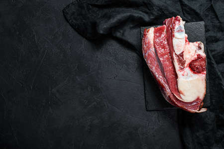 Raw beef with bone on black background. Top view. Space for text.の写真素材