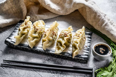 Steam Korean dumplings on a ceramic plate. Gray background. Top view.