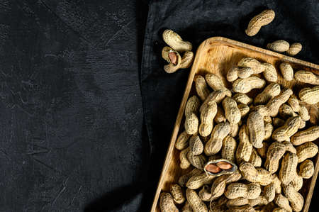 Raw unshelled peanuts in the shell. Organic groundnut. Black background. The view from the top....