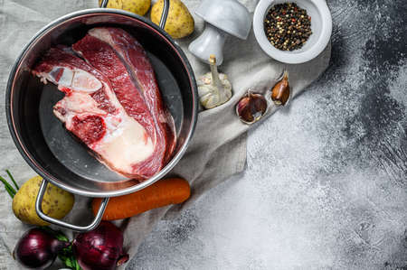 Cooking pot with bone broth meat. Vegetables cooking ingredients and spices on kitchen table. Top view. Space for text.の写真素材