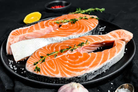 Raw salmon steak on a plate with spices. Atlantic fish. Black background. Top view.の写真素材