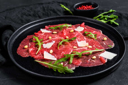 Marbled beef carpaccio with arugula and parmesan cheese. Black background. Top view.の写真素材