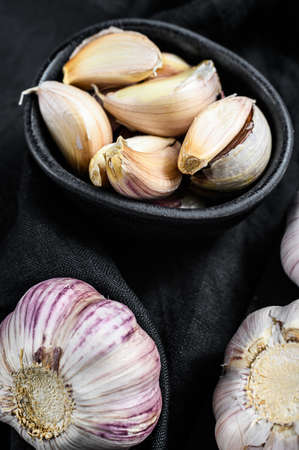 Garlic Bulb and garlic cloves on a wooden cutting Board. Organic farm food. Black background. Top...