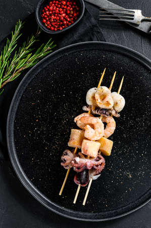 Barbecue with seafood. with shrimp, octopus, squid and mussels. Black background. Top view.の写真素材