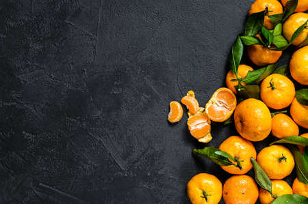 Tangerines, mandarines with leaves. Black background. Top view. Space for text.