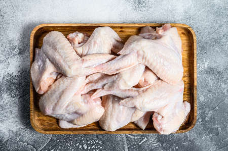 Raw chicken wings in a wooden bowl. Top view. Gray background.の写真素材