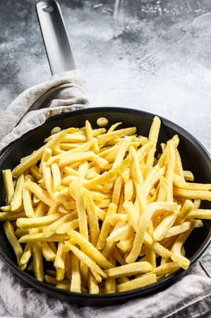 French fries in a frying pan. Gray background. Top view. Space for text.
