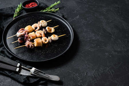 Barbecue with seafood. Kebab on wooden skewers with shrimp, octopus, squid and mussels. Black background. Top view. Space for text.の写真素材