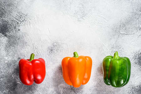 Green, orange and red bell peppers. Gray background. Top view. Space for text