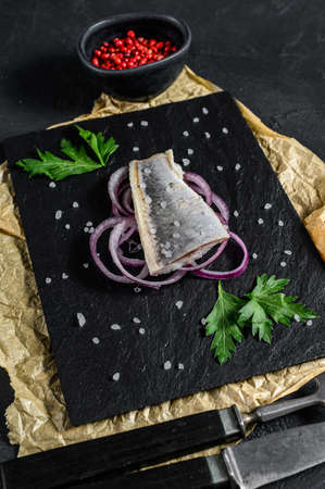 Marinated herring fillet with pepper, herbs and red onion. Black background. Top view.の写真素材