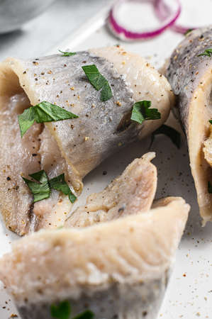 Pickled herring with parsley and red onion. Gray background. Top view.