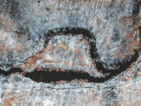 Aerial view of the river and snow-covered forest, island with trees covered with snow, winter....