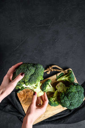 The girl is holding a fresh broccoli. Black background. Top view. Space for textの写真素材