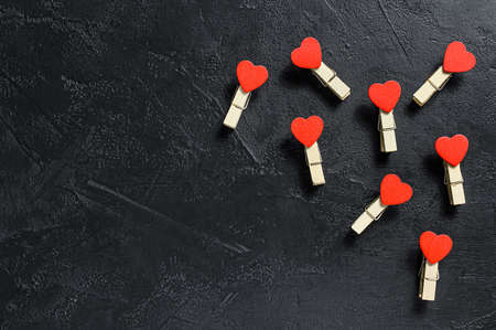 Valentines day concept. Red hearts and clothespins. black background. Top view. Space for text.