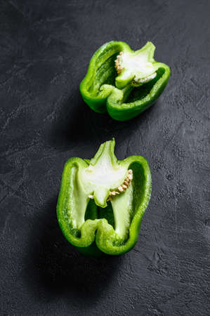 Cut green bell pepper, two halves. Black background. Top view. Space for textの写真素材