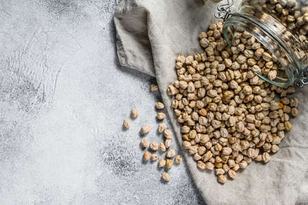 dried Chickpeas poured from a glass jar. Healthy vegetarian food. Gray background. Top view. Space for text.の写真素材