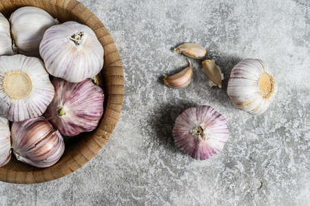 Garlic Cloves and Bulb in vintage wooden bowl. The concept of healthy eating. Gray background. Top view.の写真素材