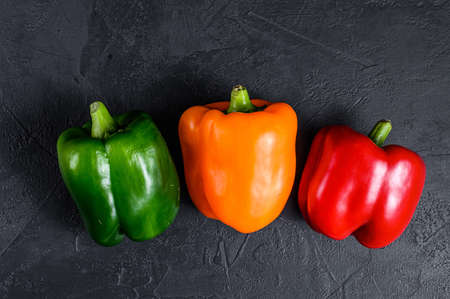 Green, orange and red bell peppers. Black background. Top view. Space for textの写真素材