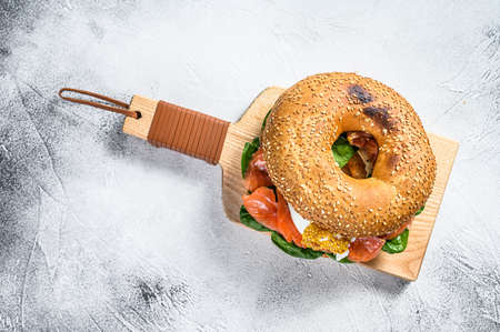 Bagel sandwich with salmon, cream cheese, spinach and egg. Gray background. Top view.の写真素材