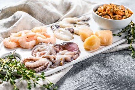 Raw seafood mix on a ceramic chopping Board. Gray background. Top viewの写真素材