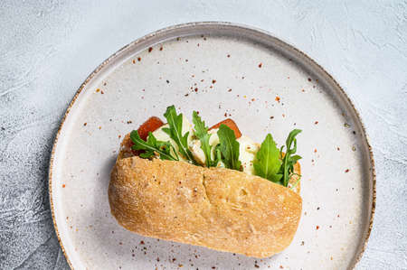 Sandwich with fresh Camembert cheese, pear marmalade, ricotta and arugula. Gray background. Top...