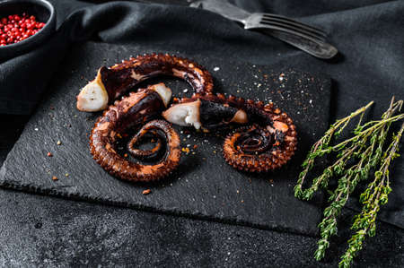 Grilled octopus tentacles. Fresh seafood. Black background. Top view.