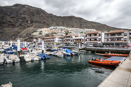 Yachts and boats in the port on the background of volcanic mountains. Selective focus. 20.01.2020 Los Gigantes, Tenerife.のeditorial素材
