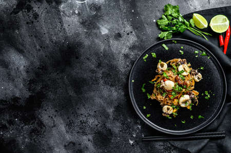 Homemade stir fry damage noodles with seafood and vegetables in a plate. Black background. Top view. Copy space.の写真素材