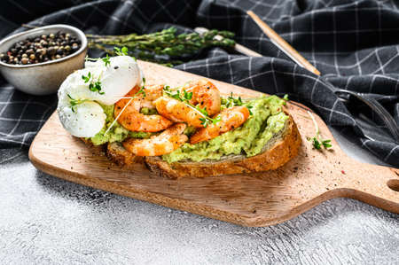 Sandwich with bread, avocado, shrimps, prawns and soft boiled egg. Gray background. Top view.の写真素材