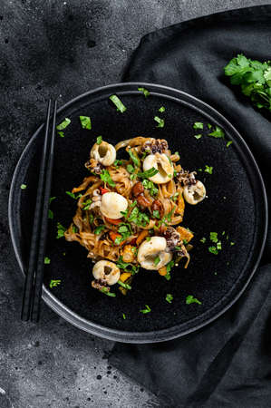 Asian stir fry Noodles with cuttlefish and vegetables. Black background. Top view.の写真素材
