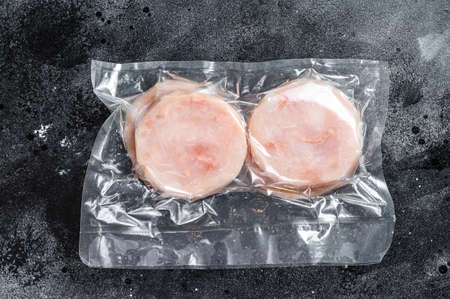 Fish cutlets from minced cod in a vacuum package. Black background. Top view.の写真素材