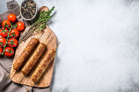 Homemade pork meat kebabs on skewers. White background. Top view. Copy space.