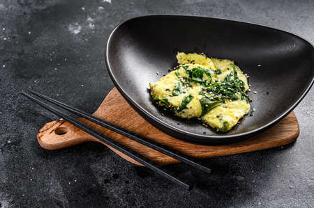 Spinach and Cheese Omelet with sesame seeds. Black background. Top view.