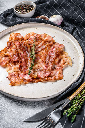 Fried pork bacon with a sprig of thyme. Organic meat. Gray background. Top view.