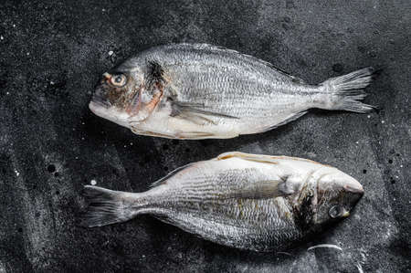 Sea bream fish. Mediterranean cuisine, healthy cooking concept. black background. top view