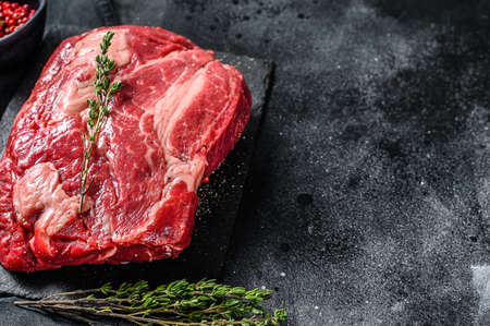 Raw Chuck eye roll steak. Organic beef. Black background. Top view. Copy space.