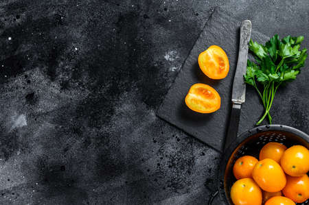 Fresh yellow tomato cut in half. Black background. Top view. Copy space.の写真素材