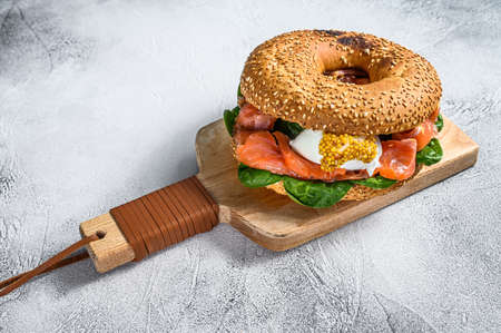 Bagel with salted salmon, cream cheese, avocado and egg. Gray background. Top view.