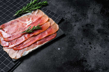 prosciutto crudo, italian salami, parma ham. Antipasto plate. Black background, top view, space for...