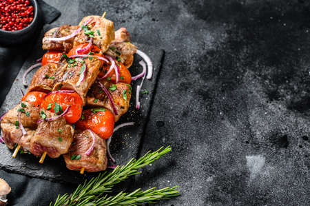 Shish kebab with onion and tomato. Grilled meat skewers. Black background. Top view. Copy space.の写真素材