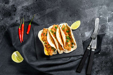 Mexican carnitas tacos with parsley, cheese and chili pepper. Black background. Top view. Copy space.の写真素材