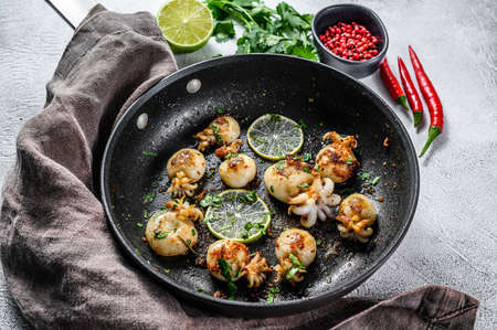 Mini grilled squid with lime and spices in a pan. Gray background. Top view.の写真素材