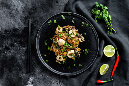Asian stir fry Noodles with cuttlefish and vegetables. Black background. Top view.の写真素材
