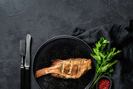 Red sea bass baked. Black background. Top view. Space for text.