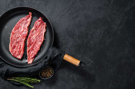 Raw flank steak in a pan. Marble beef black Angus. Black background. Top view. Space for text.の写真素材