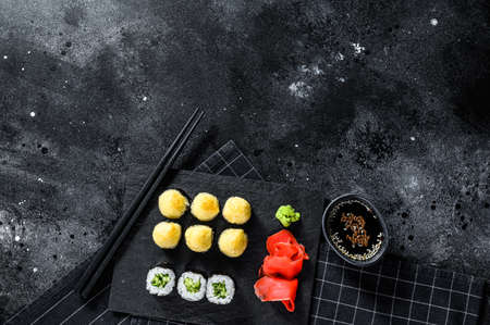 sushi rolls with cucumber, salmon and shrimp on a stone tray. Black background. Top view. Space for text.の写真素材