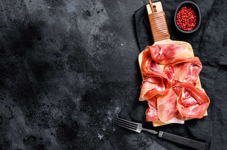 Spanish jamon Serrano, ham. Black background, top view, space for text.